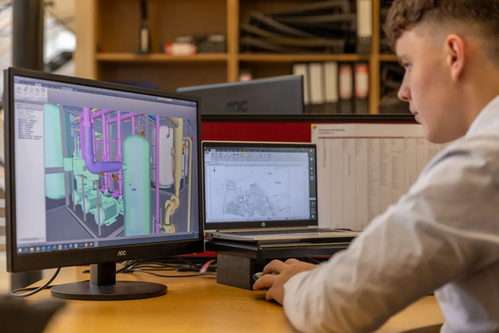 An engineer working in CAD software across two monitors