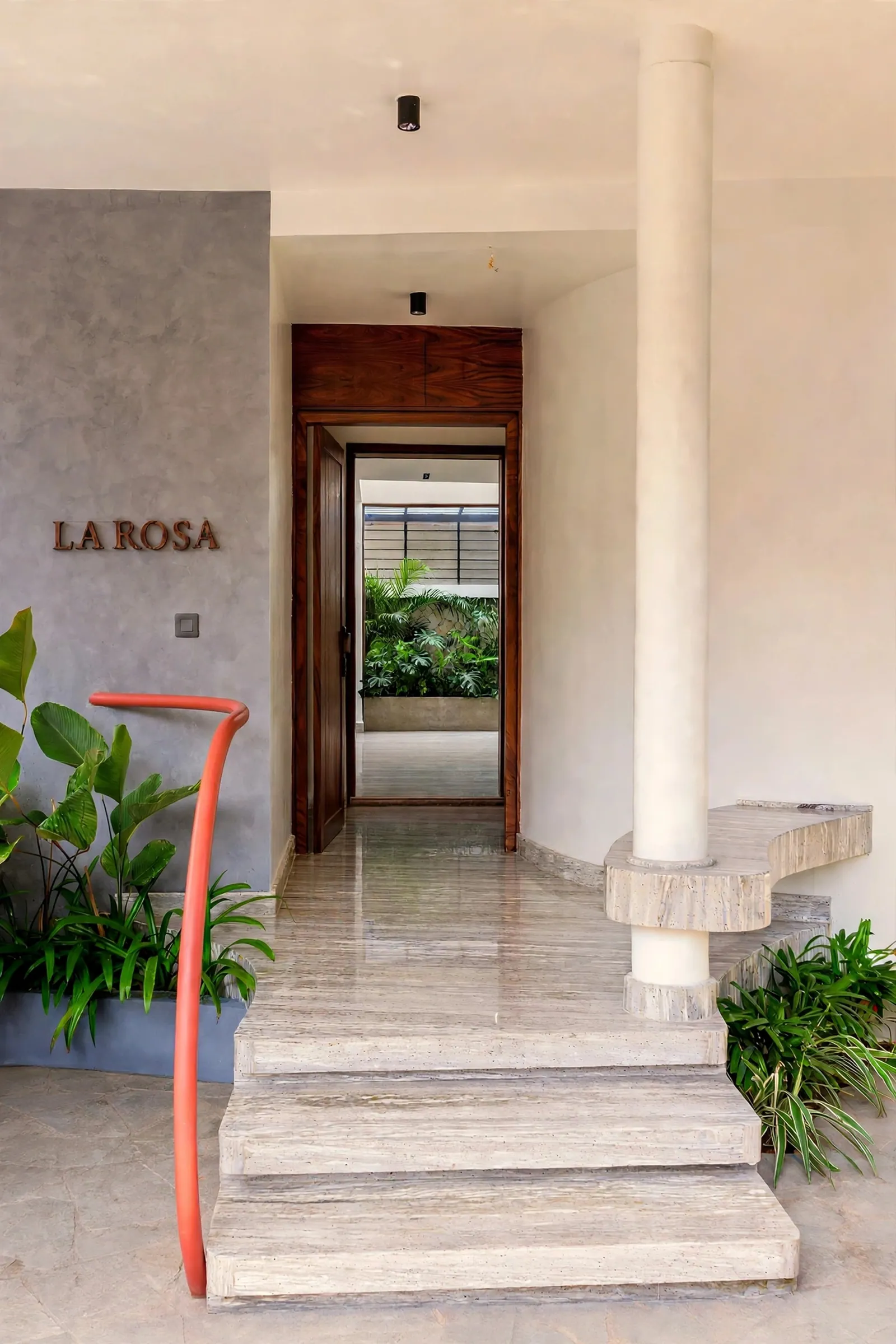 Stone steps, a grey plaster wall and the first glimpse of the red handrail