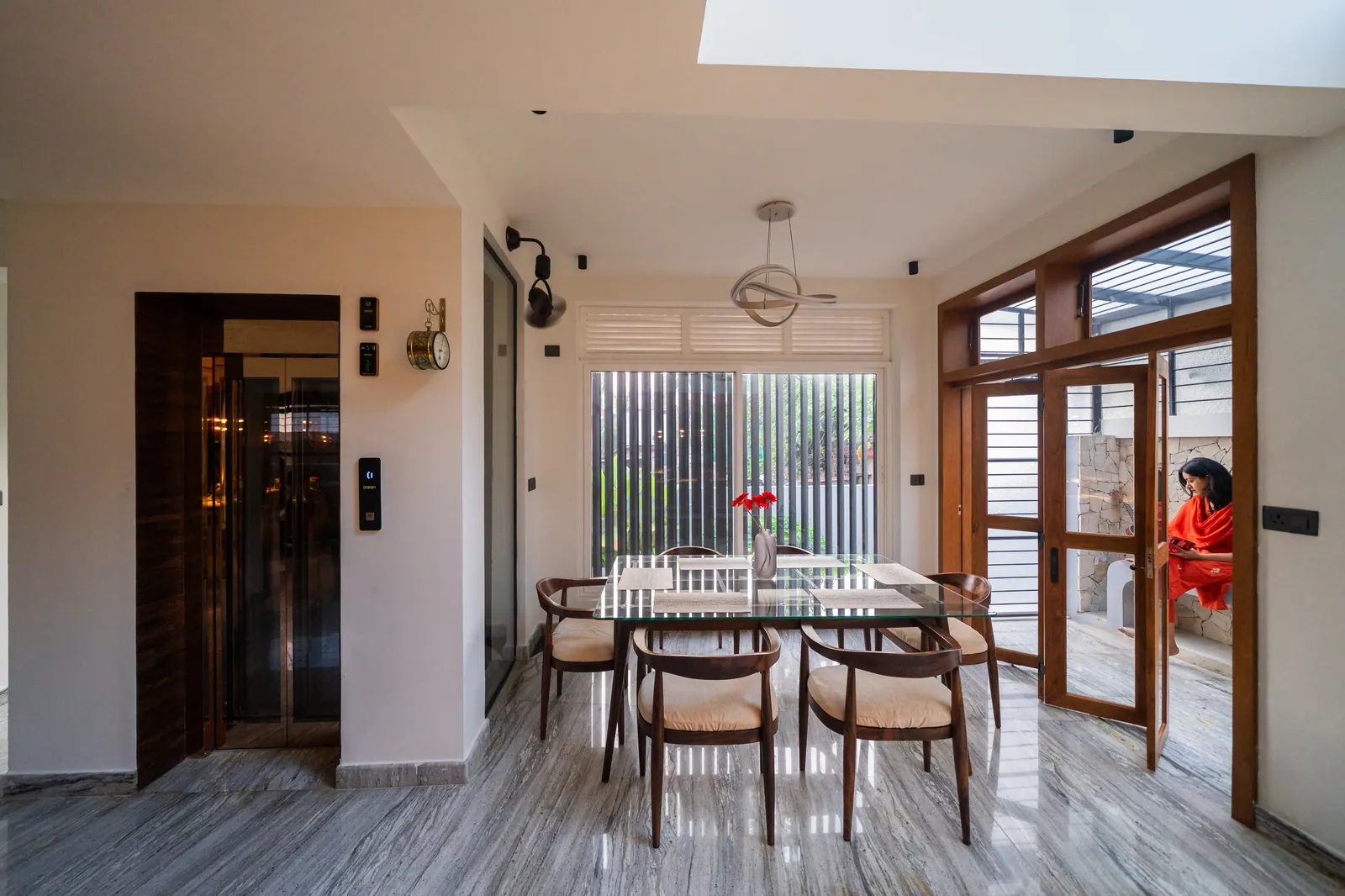 Dining beside full-height timber-framed glazing and vertical screens