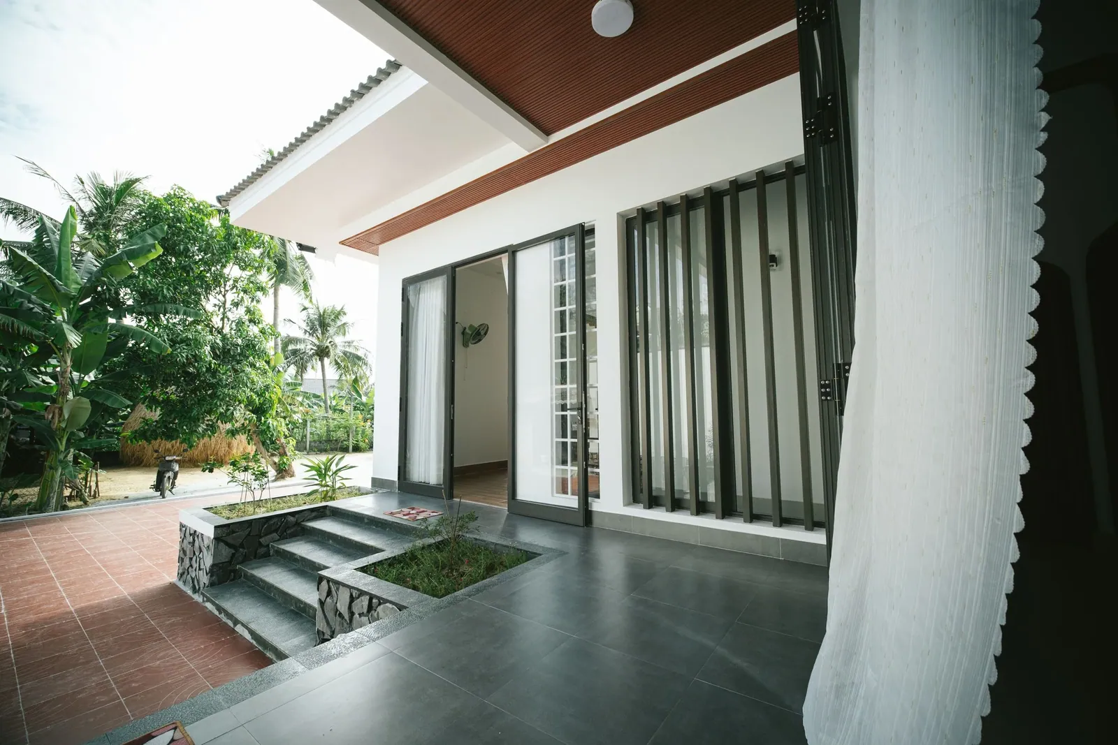 A shaded verandah under a deep overhang opening onto a garden