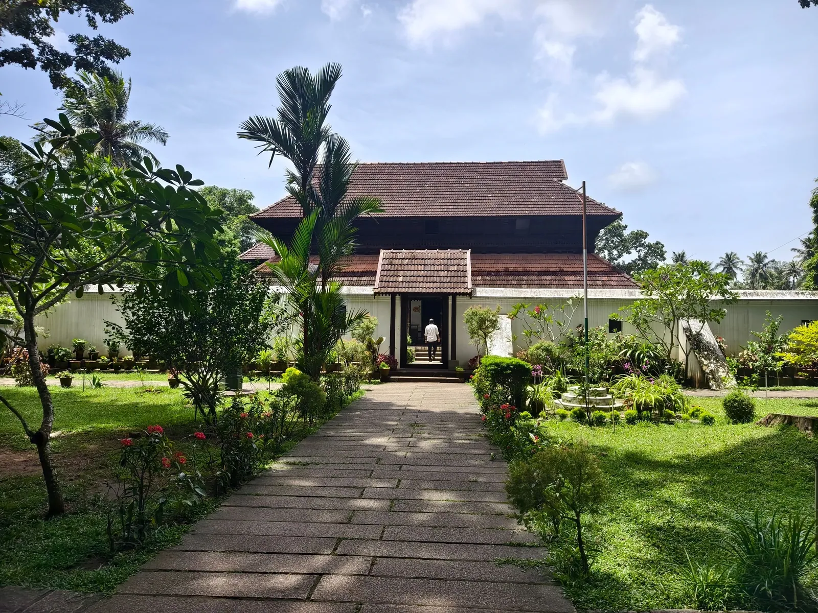 Traditional Kerala house surrounded by tropical greenery and a garden pathway