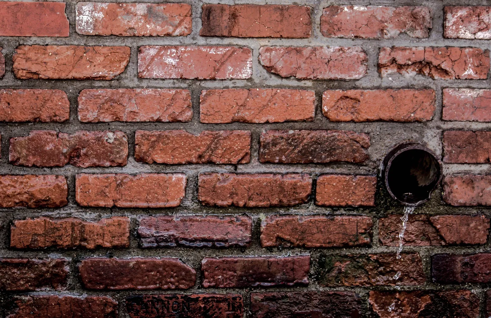 Water discharging from a pipe through brickwork