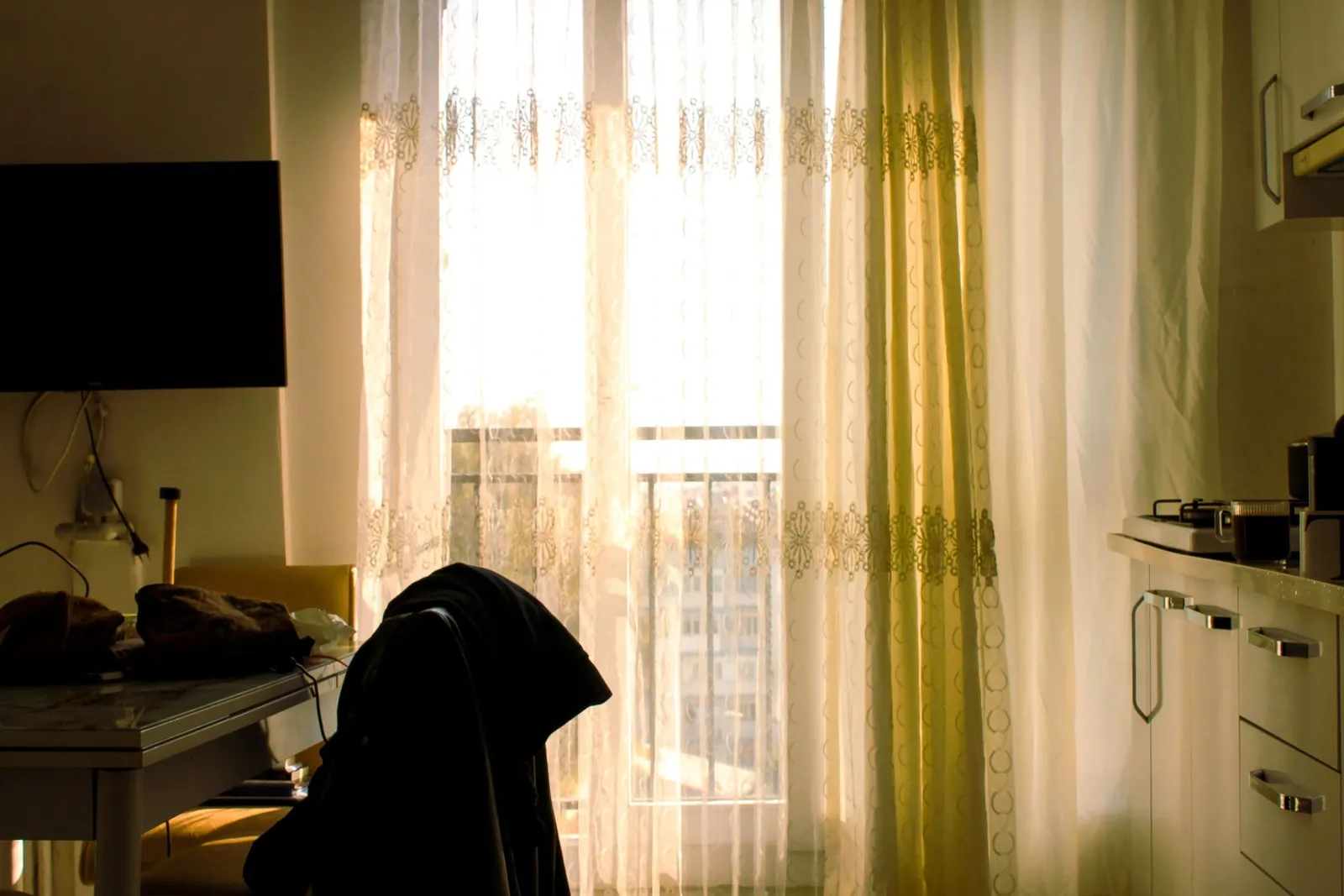 Sunlight entering an apartment through sheer curtains