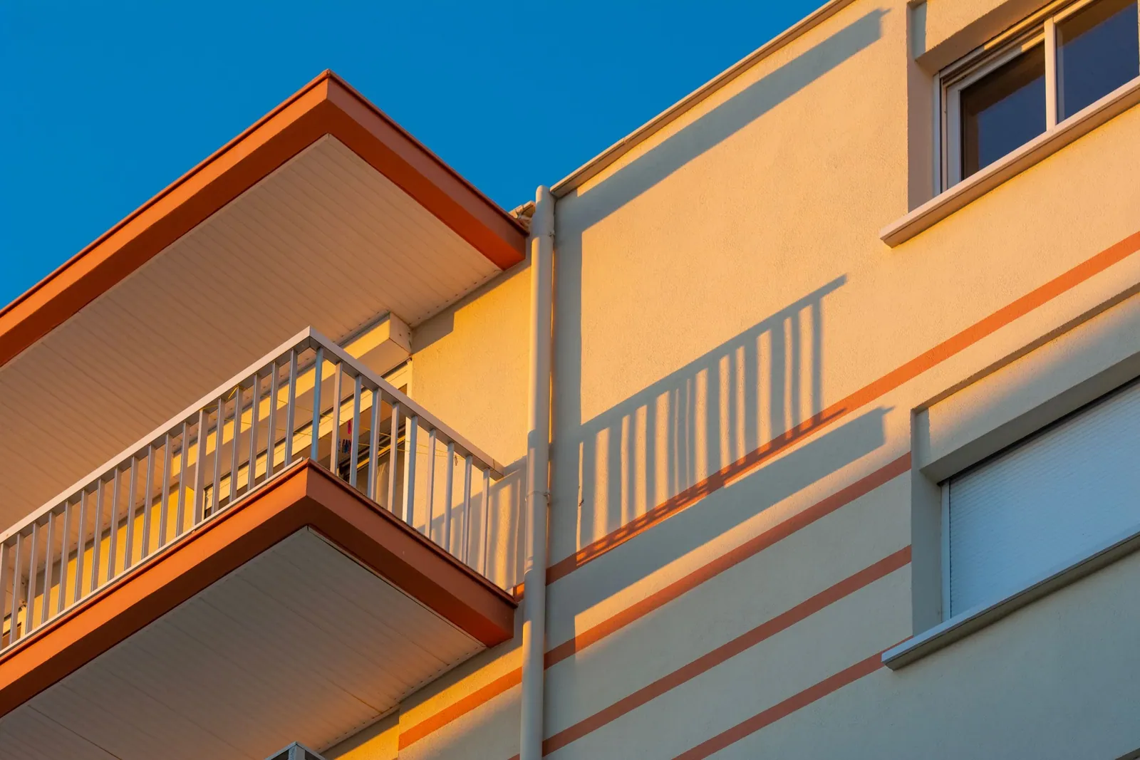 Apartment façade with balconies in sunlight and shadow